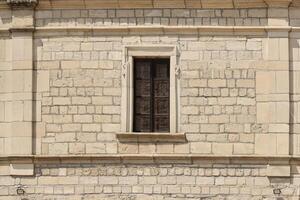 Very old window in brick stone wall of castle or fortress of 18th century. Full frame wall with window photo