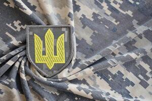 Symbol of Ukrainian army on the camouflage uniform of a Ukrainian soldier. The concept of war in Ukraine, patriotism and protecting your country from occupiers photo