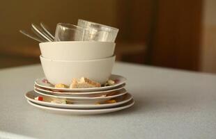 Stack of dirty dishes with food leftovers on the table after meal. Banquet ending concept. Unwashed dishes photo