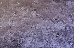 Close up of muddy puddle with small stones on wet surface. Background texture with top view photo