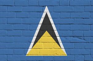 Saint Lucia flag depicted in paint colors on old brick wall. Textured banner on big brick wall masonry background photo
