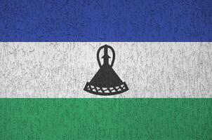 Lesotho flag depicted in bright paint colors on old relief plastering wall. Textured banner on rough background photo