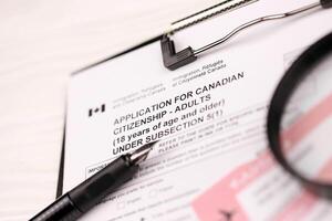 Application for Canadian citizenship for adults on A4 tablet lies on office table with pen and magnifying glass photo