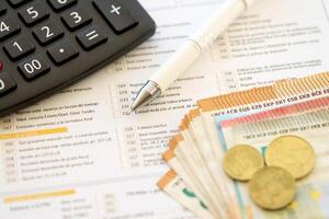 Filling italian tax form process with pen, calculator and euro money bills close up. Tax paying period photo