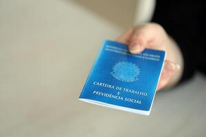 Woman boss gives a brazilian work card and social security blue book to us in employment office photo