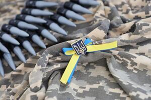 ucranio símbolo y un máquina pistola cinturón en el camuflaje uniforme de un ucranio soldado. el concepto de guerra en Ucrania, patriotismo y proteger tu país desde ocupantes foto