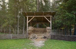 Place with stacks of hay cubes and rustic wooden wheels of old cart photo