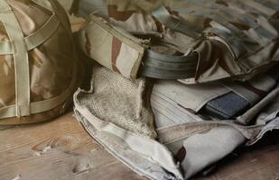 A military helmet of a Ukrainian soldier with a heavy bulletproof vest on wooden table in checkpoint dugout photo