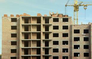 View of a large construction site with buildings under construction and multi-storey residential homes. Tower cranes in action on blue sky background. Housing renovation concept photo