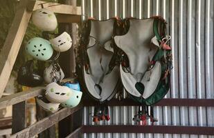 Climbing equipment - colorful helmets and safety vests hanging on a board in a rope park photo