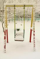 Children's swing, covered with a thick layer of snow after a heavy snowfall photo