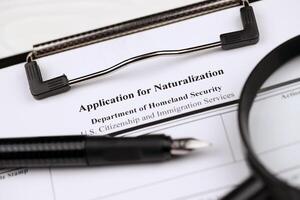 N-400 Application for Naturalization blank form on A4 tablet lies on office table with pen and magnifying glass photo