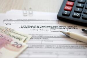 Information on amount of income or loss from non-agricultural economic activity, PIT-B form on accountant table with pen and polish zloty money bills photo