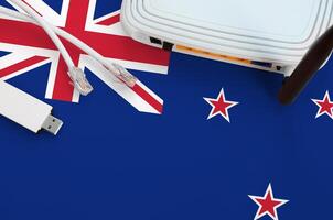 New Zealand flag depicted on table with internet rj45 cable, wireless usb wifi adapter and router. Internet connection concept photo