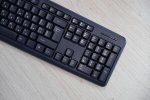 Small compact black gaming computer keyboard on a table made of wooden pine boards. Wireless keyboard with mechanical switches for gadgets and computer photo