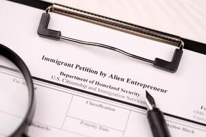 I-526 Immigrant Petition by Alien Entrepreneur blank form on A4 tablet lies on office table with pen and magnifying glass photo