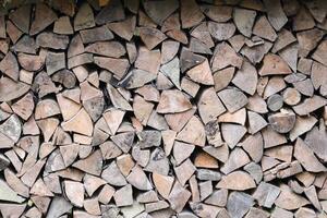 Firewood stacked near the wooden wall of old hut. Many chopped logs of firewood photo