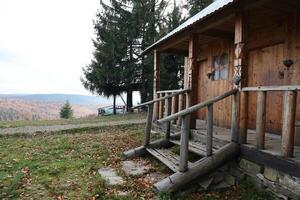 Small wooden house among trees and mountains in the middle of nature on an autumn photo