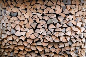 Firewood stacked near the wooden wall of old hut. Many chopped logs of firewood photo