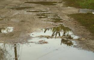 Photo of a fragment of a destroyed road with large puddles in rainy weather