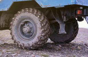 Wheel closeup in a countryside landscape with a mud road. Off-road 4x4 suv automobile with ditry body after drive in muddy road photo