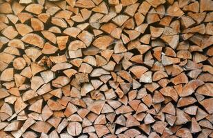 Firewood stacked near the wooden wall of old hut. Many chopped logs of firewood photo