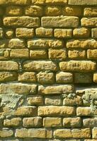 Vertical wall texture of several rows of very old brickwork made of red brick. Shattered and damaged brick wall with pinched corners photo