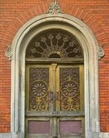 Texture front part of an ancient brick crypt with a patterned wooden door in the cemetery photo