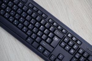 Small compact black gaming computer keyboard on a table made of wooden pine boards. Wireless keyboard with mechanical switches for gadgets and computer photo