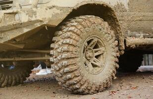 Wheel closeup in a countryside landscape with a mud road. Off-road 4x4 suv automobile with ditry body after drive in muddy road photo