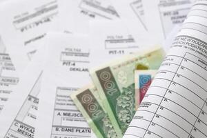 Polish zloty money on big amount of polish tax forms close up. Accounting, bureaucracy and taxpayers routine photo