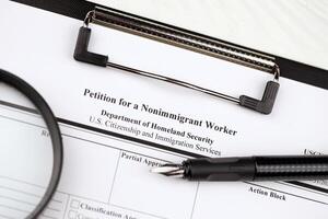 I-129 Petition for a nonimmigrant worker blank form on A4 tablet lies on office table with pen and magnifying glass photo