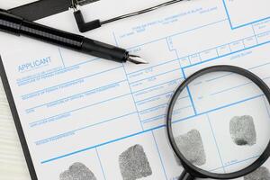 Fingerprints card police form on A4 tablet lies on office table with pen and magnifying glass photo