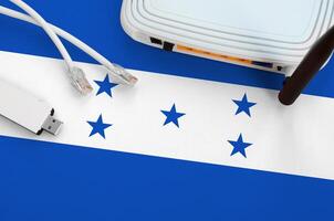 Honduras flag depicted on table with internet rj45 cable, wireless usb wifi adapter and router. Internet connection concept photo