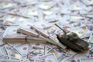 juguete tanque en nosotros cien dólar cuentas Billetes el concepto de guerra costos, militar gasto y económico crisis foto