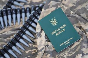 Ukrainian military ID on fabric with texture of pixeled camouflage. Cloth with camo pattern in grey, brown and green pixel shapes with Ukrainian army personal token photo