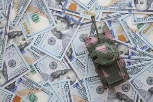 Toy tank on US hundred dollar bills banknotes. The concept of war costs, military spending and economic crisis photo