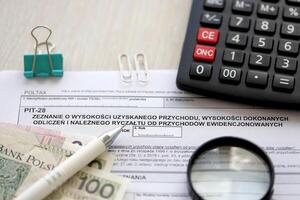 Declaration of amount of income obtained, amount of deductions made and lump sum due from recorded income, PIT-28 form on accountant table with pen and polish zloty money bills photo