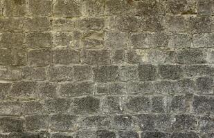 Very old brick stone wall of castle or fortress of 18th century. Full frame wall with obsolete dirty and cracked bricks photo