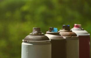 A few used aerosol paint sprayers lie on the windowsill in the workshop of a graffiti artist. The concept of street art and illegal drawing on the walls. Youth hobby photo