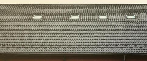 el textura de el techo con un techo hecho de metal, cubierto con gotas desde el lluvia. varios cristal ventanas son construido dentro el techo foto