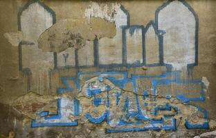 An old concrete wall with boneless plaster, spoiled by colored graffiti drawings photo