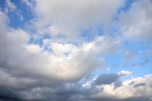 Beautiful cloud formations in the sky with sunlight behind. White clouds on dramatic blue sky photo