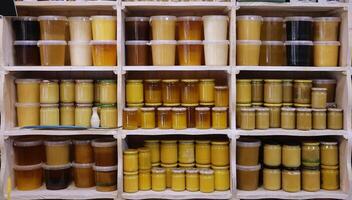 Jars of different honey varieties stocked on a shelf. Lavender, linden and mixed honey photo