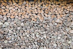 Firewood stacked near the wooden wall of old hut. Many chopped logs of firewood photo