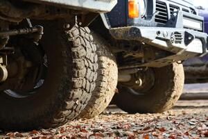 Wheel closeup in a countryside landscape with a mud road. Off-road 4x4 suv automobile with ditry body after drive in muddy road photo