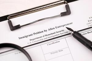 I-526 Immigrant Petition by Alien Entrepreneur blank form on A4 tablet lies on office table with pen and magnifying glass photo