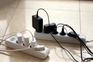 Overloaded power boards. Power strips with different electrical plugs on white floor photo