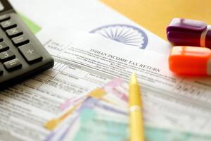 Indian income tax return blank form with pen and indian rupees bills photo