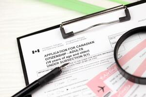 Application for Canadian citizenship for adults on A4 tablet lies on office table with pen and magnifying glass photo
